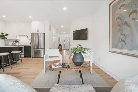 a living room with furniture a refrigerator and a flat screen tv
