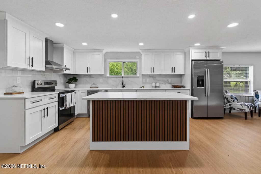 43739 Ratliff Road Callahan, FL 32011 - Photo 23 of 55 a kitchen with stainless steel appliances granite countertop a stove a sink dishwasher a refrigerator and white cabinets with wooden floor