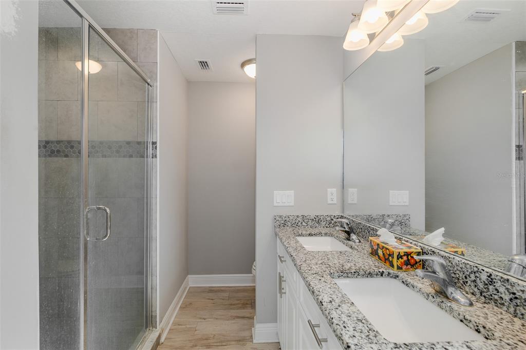 6823 Crossbow Lane New Port Richey, FL 34653 - Photo 13 of 25 a bathroom with a granite countertop sink a mirror and shower