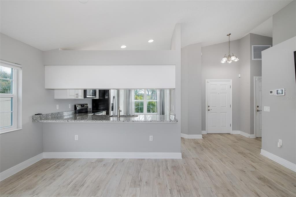 6823 Crossbow Lane New Port Richey, FL 34653 - Photo 5 of 25 a view of a living room a kitchen with wooden floor and a large window
