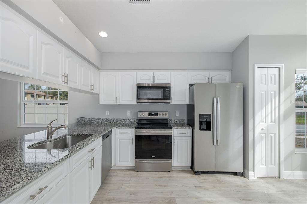 6823 Crossbow Lane New Port Richey, FL 34653 - Photo 6 of 25 a kitchen with stainless steel appliances granite countertop a refrigerator sink and stove