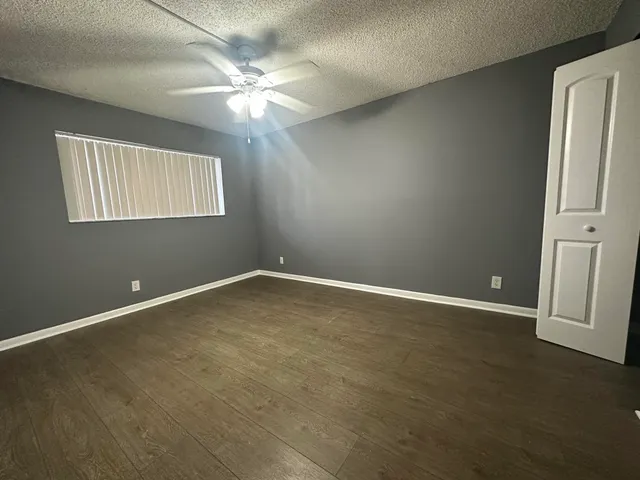 an empty room with windows and fan