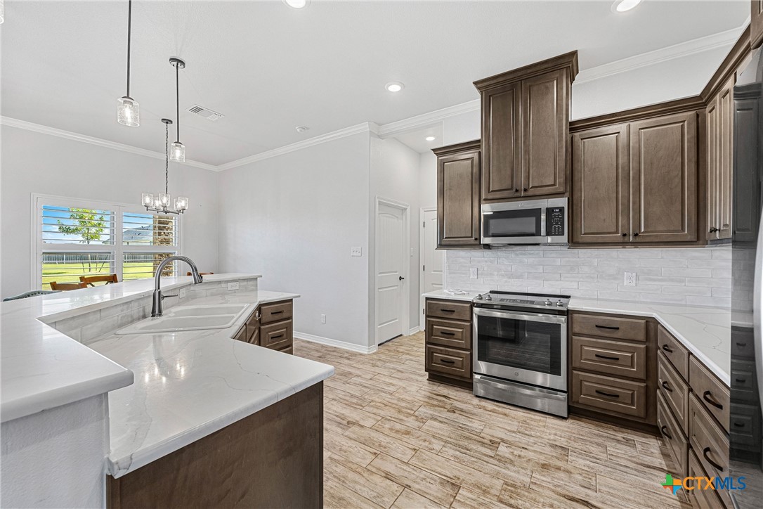 5513 Hollow Loop Salado, TX 76571 - Photo 13 of 37 a kitchen with stainless steel appliances kitchen island granite countertop a sink and a stove top oven with wooden floor