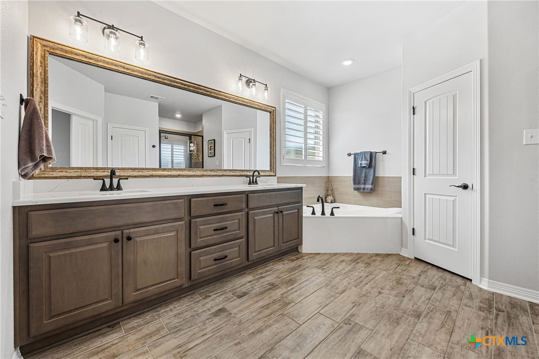 5513 Hollow Loop Salado, TX 76571 - Photo 21 of 37 a large white bathroom with a double vanity sink a mirror and a bathtub