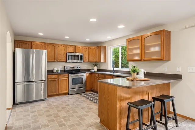 a kitchen with stainless steel appliances granite countertop a refrigerator a stove a sink a oven with a dining table and chairs