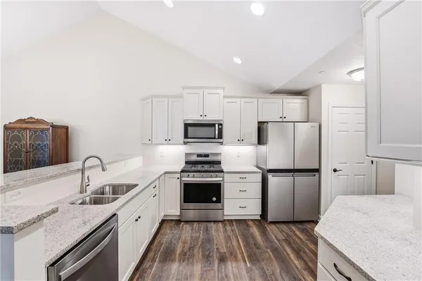 a kitchen with granite countertop a sink stove and refrigerator