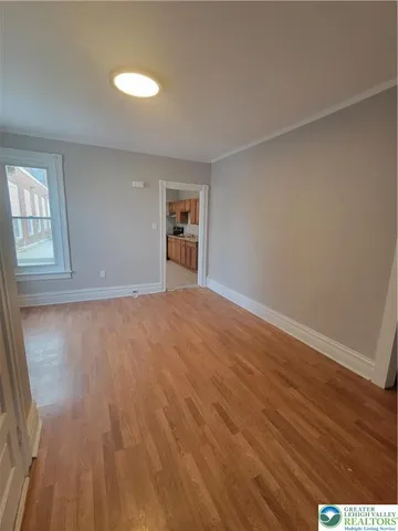 a view of empty room with wooden floor and fan
