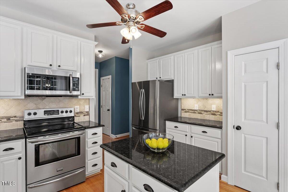 5112 Solemn Grove Road Garner, NC 27529 - Photo 18 of 56 a kitchen with stainless steel appliances a stove a refrigerator a microwave a sink and cabinets
