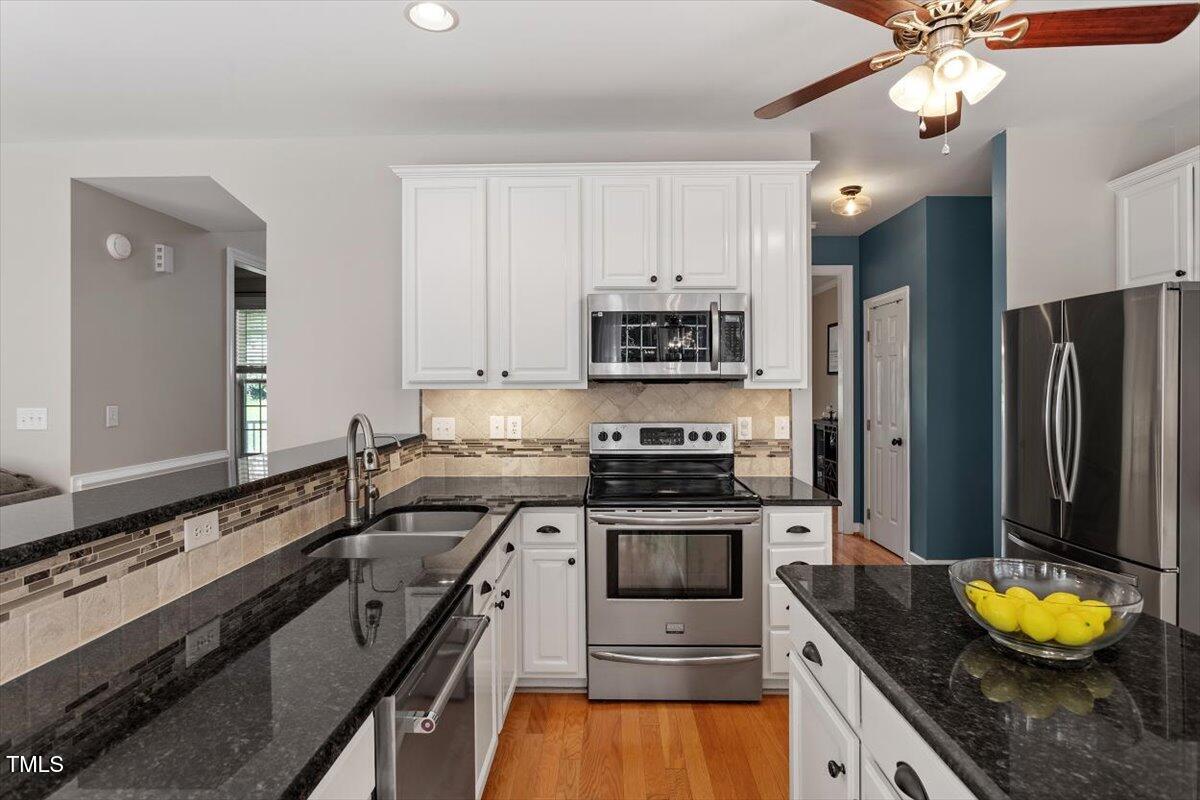 5112 Solemn Grove Road Garner, NC 27529 - Photo 20 of 56 a kitchen with granite countertop a sink stainless steel appliances and white cabinets