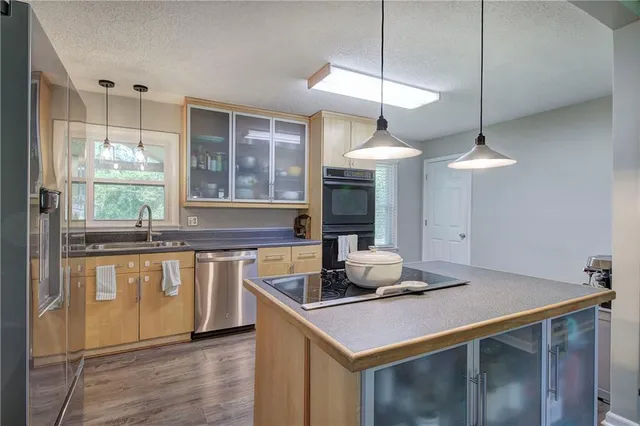 a kitchen with stainless steel appliances granite countertop a sink a stove and a wooden floors