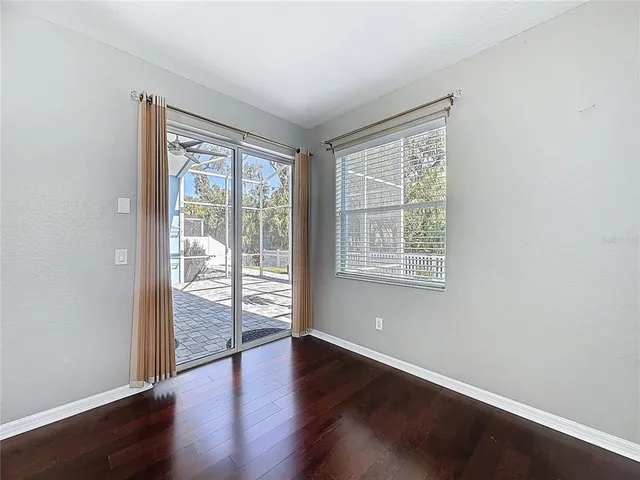 a view of an empty room with window and wooden floor