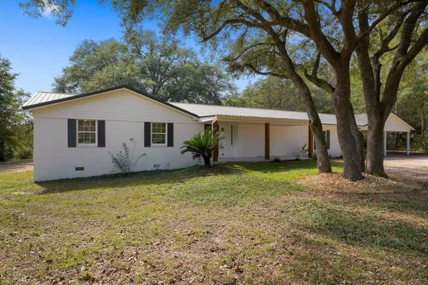 a view of a house with a backyard and tree
