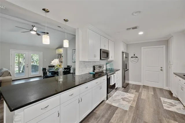 a large white kitchen with a lot of counter space and wooden floor