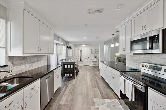 a kitchen with stainless steel appliances a sink a stove top oven a counter space and cabinets