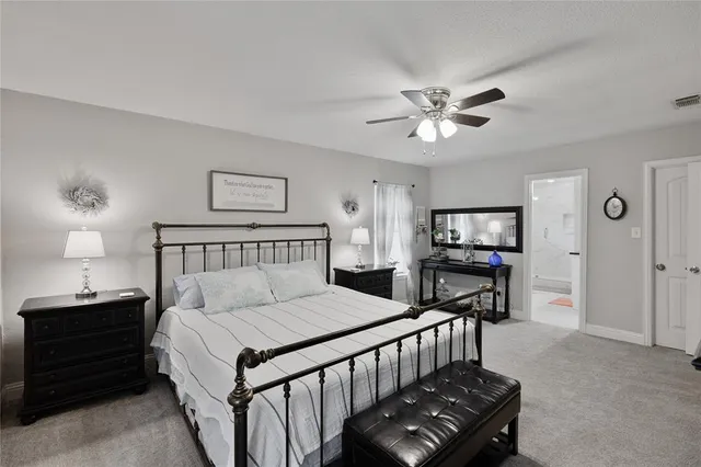 a bedroom with a bed a dresser and a chandelier