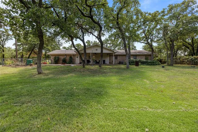 a view of a house with a big yard and a large tree