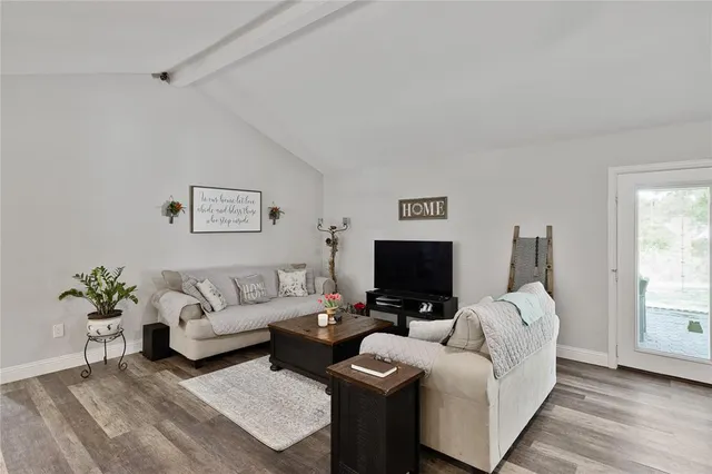 a living room with furniture a flat screen tv and a window