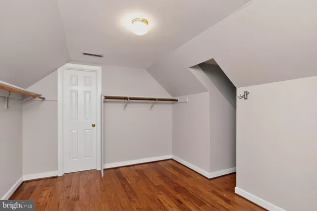 an empty room with wooden floor and a ceiling fan