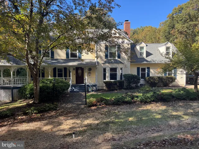 a view of a white house next to a yard with plants and trees