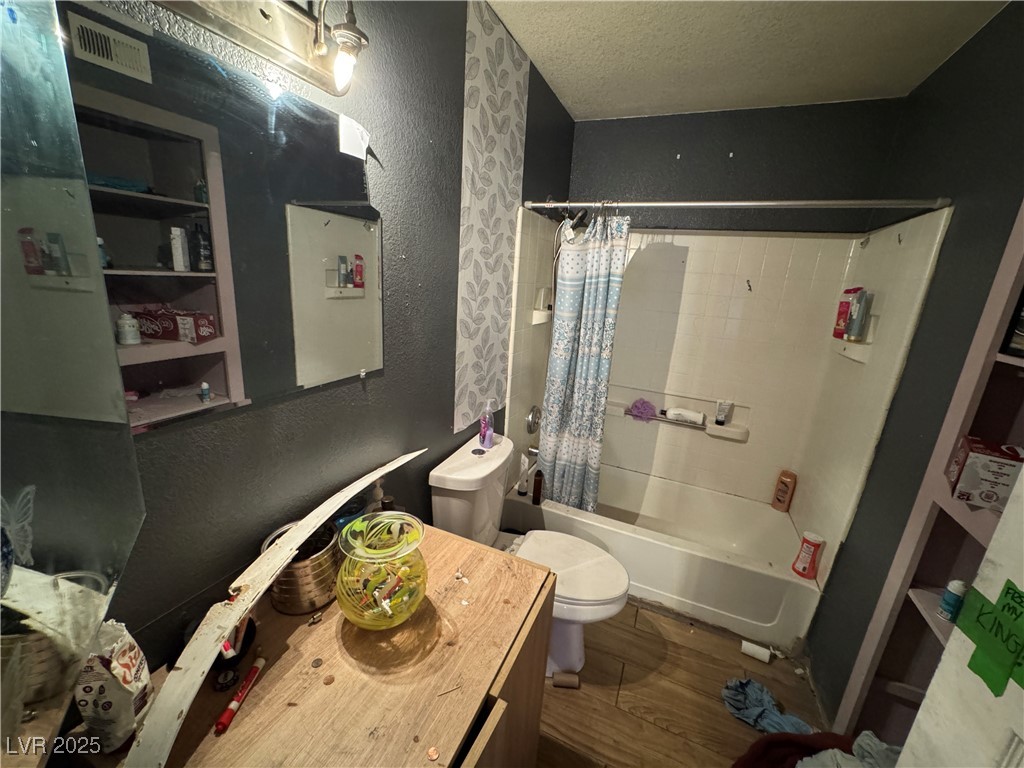 3318 North Decatur Boulevard, Unit 2057 Las Vegas, NV 89130 - Photo 13 of 18 Bathroom with a textured ceiling, a textured wall, shower / tub combo with curtain, dark wood-type flooring, and vanity