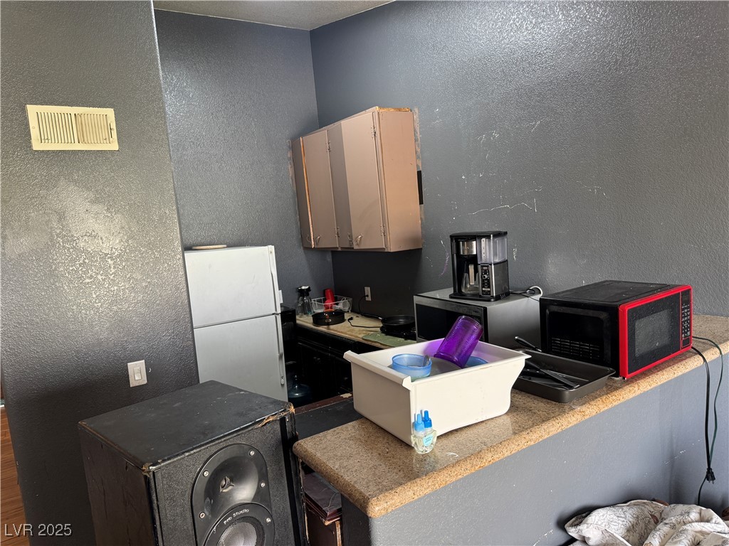 3318 North Decatur Boulevard, Unit 2057 Las Vegas, NV 89130 - Photo 5 of 18 Kitchen with a textured wall and freestanding refrigerator