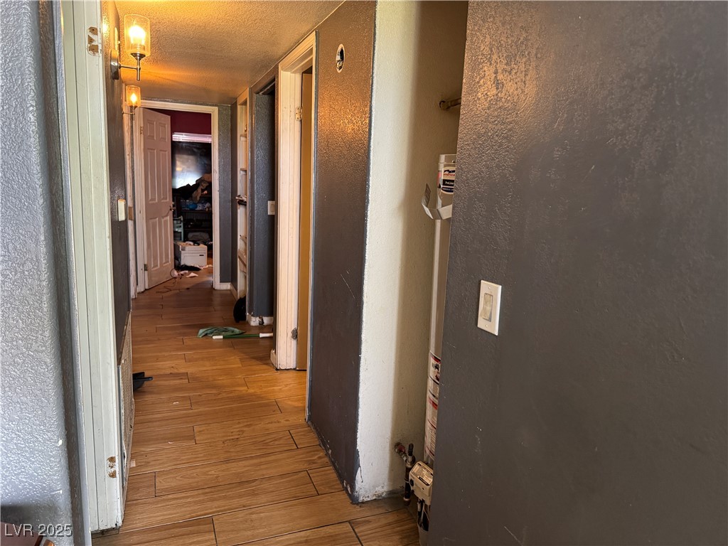 3318 North Decatur Boulevard, Unit 2057 Las Vegas, NV 89130 - Photo 8 of 18 Corridor featuring a textured wall, light wood finished floors, and a textured ceiling