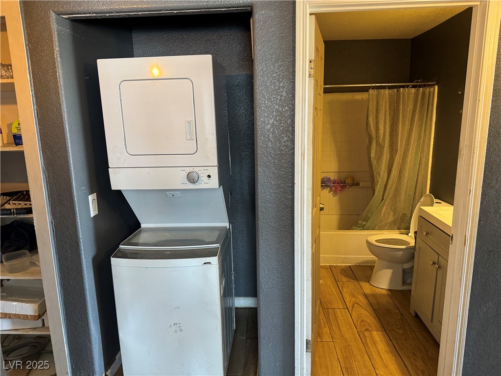 3318 North Decatur Boulevard, Unit 2057 Las Vegas, NV 89130 - Photo 10 of 18 Washroom featuring light wood-style flooring, stacked washing machine and dryer, and a textured wall