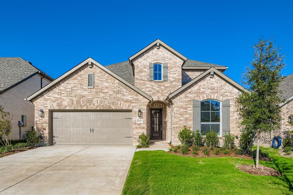 4115 Windy Point Court Oak Point, TX 75068 - Photo 1 of 1 French country home with brick siding, concrete driveway, a garage, a front yard, and roof with shingles