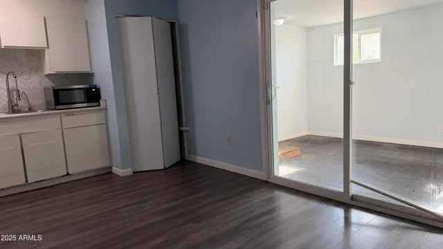 a kitchen with wooden floor and electronic appliances