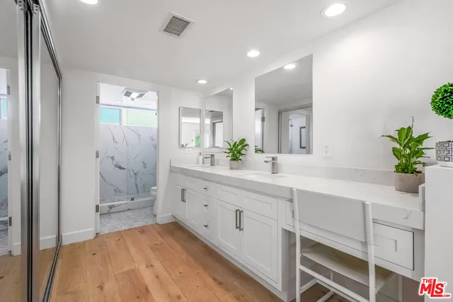 a spacious bathroom with a double vanity sink a mirror and a shower