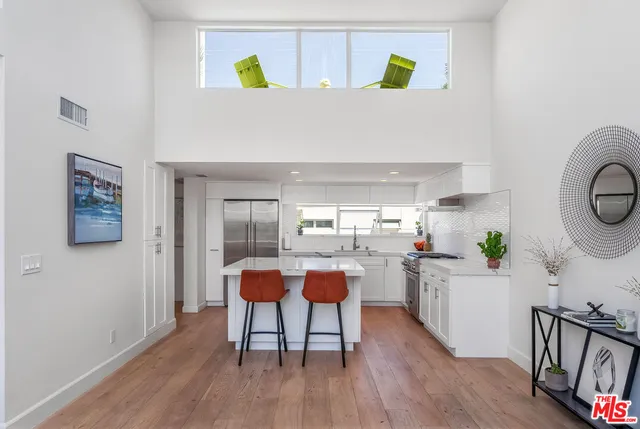 a living room with stainless steel appliances furniture and a wooden floor