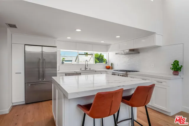 a kitchen with stainless steel appliances granite countertop a table chairs in it and wooden floors