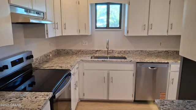 a kitchen with stainless steel appliances granite countertop a sink stove and cabinets