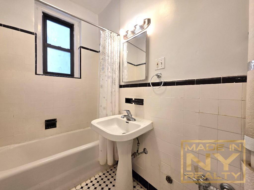25-74 33rd Street, Unit 5H Queens, NY 11102 - Photo 4 of 4 a bathroom with a sink a mirror and a bathtub