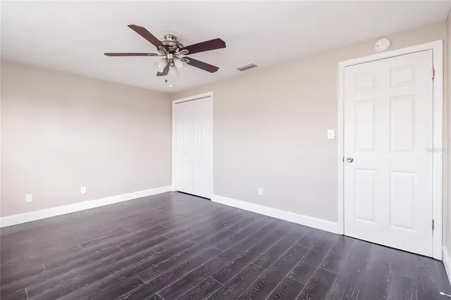 an empty room with wooden floor and ceiling fan