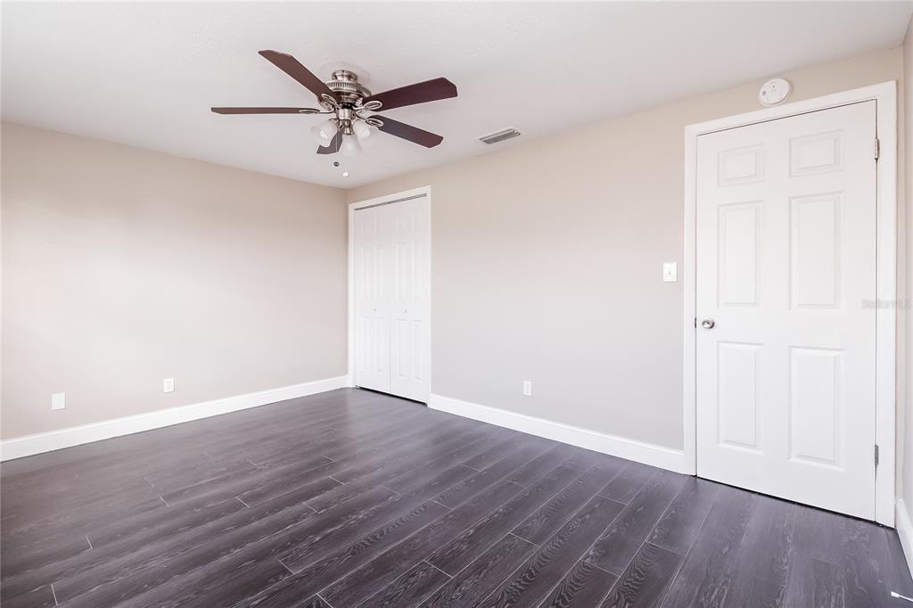 6230 Westport Drive Port Richey, FL 34668 - Photo 11 of 15 an empty room with wooden floor and ceiling fan