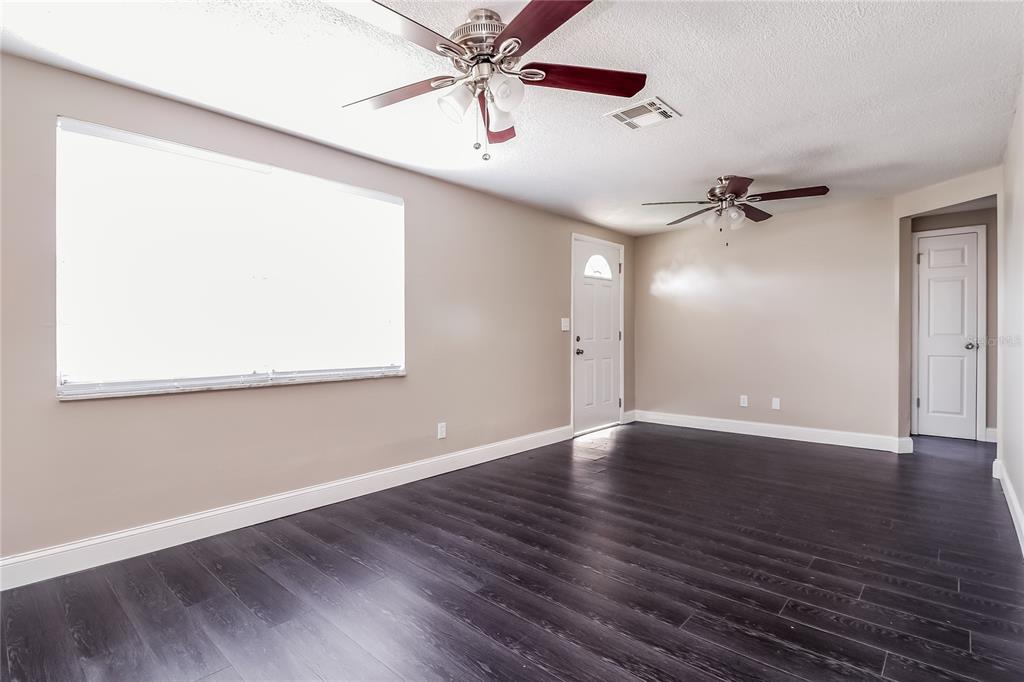 6230 Westport Drive Port Richey, FL 34668 - Photo 4 of 15 an empty room with wooden floor chandelier fan and windows