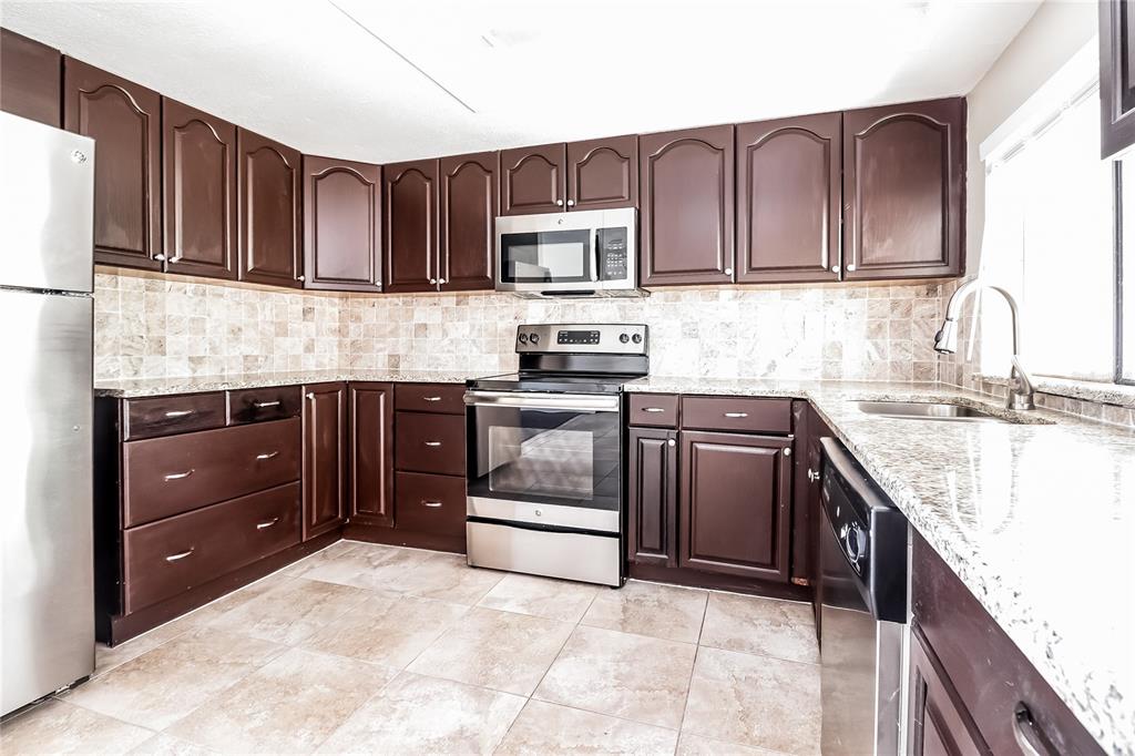 6230 Westport Drive Port Richey, FL 34668 - Photo 6 of 15 a kitchen with stainless steel appliances granite countertop wooden cabinets sink stove and microwave
