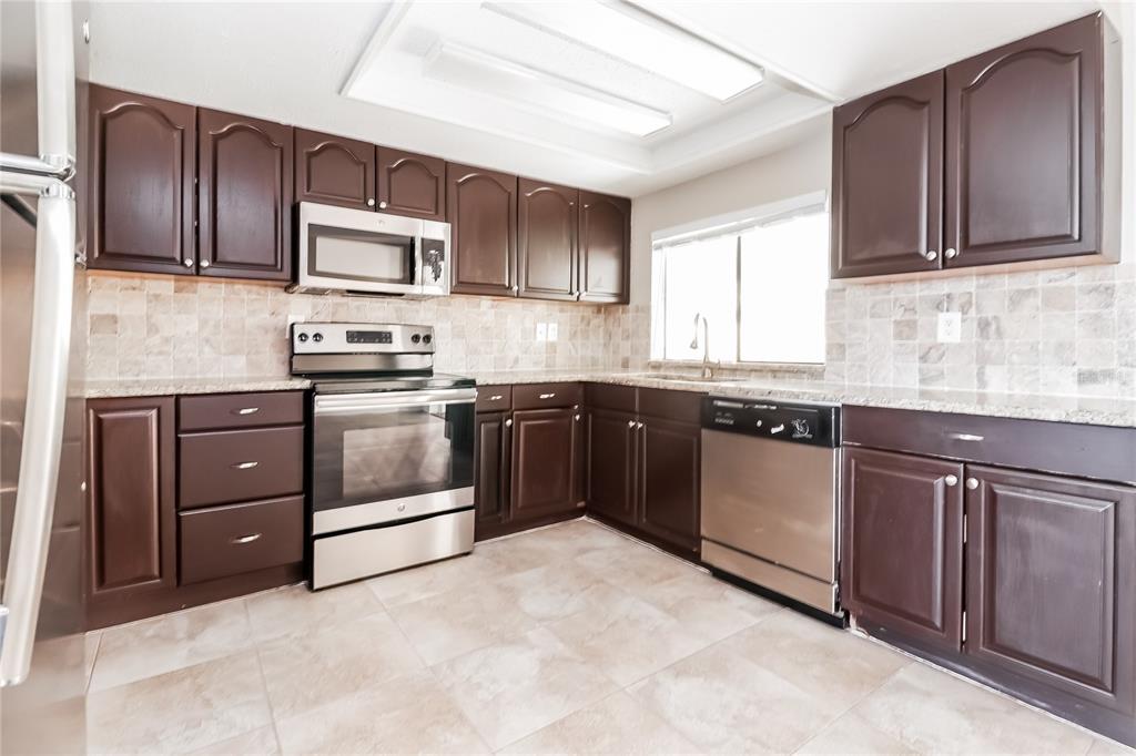 6230 Westport Drive Port Richey, FL 34668 - Photo 7 of 15 a kitchen with stainless steel appliances granite countertop a stove a sink dishwasher and a refrigerator