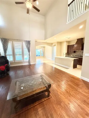a living room with kitchen island stainless steel appliances furniture a flat screen tv and a chandelier