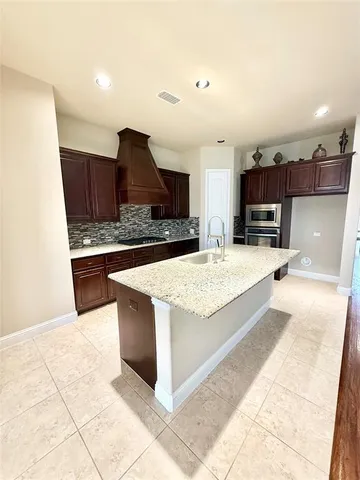a kitchen with stainless steel appliances kitchen island granite countertop a refrigerator and a stove top oven