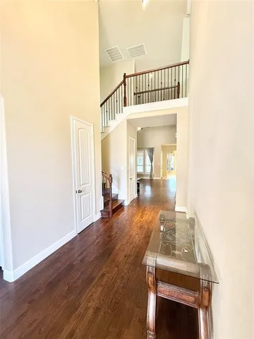 a view of a hallway to a livingroom with wooden floor and furniture
