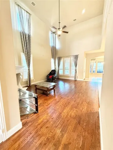 a living room with a floor to ceiling window and wooden floor