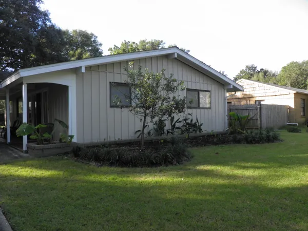 a backyard of a house with plants and barbeque oven