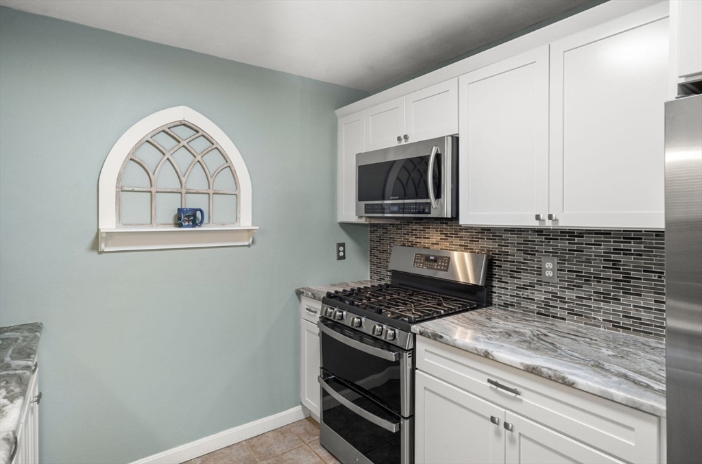 7 Greenbriar Drive, Unit 304 North Reading, MA 01864 - Photo 7 of 23 a kitchen with granite countertop a stove top oven microwave and cabinets