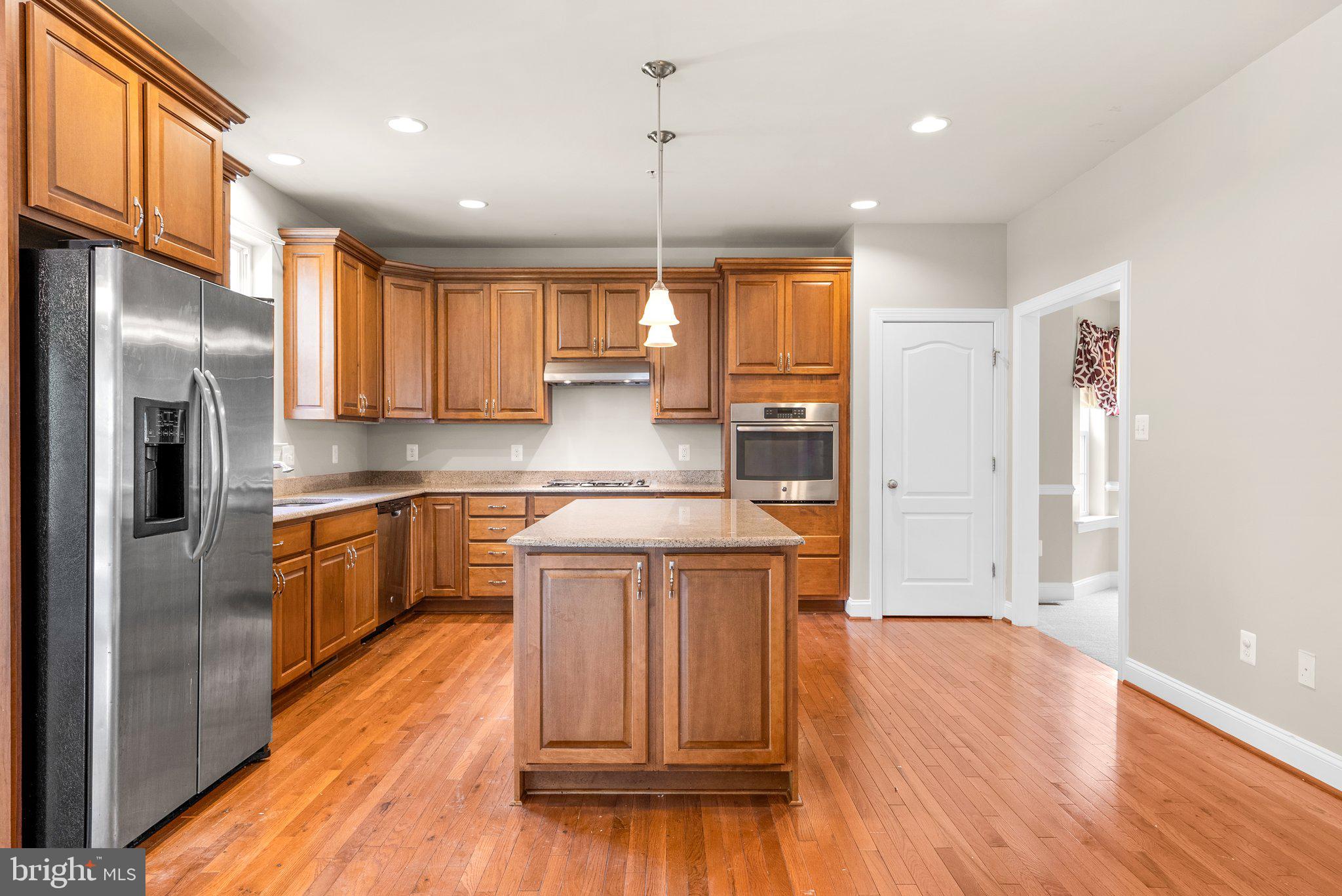 9602 Pep Rally Lane Waldorf, MD 20603 - Photo 14 of 44 a kitchen with stainless steel appliances granite countertop a refrigerator a sink dishwasher a stove and white countertops with wooden floor