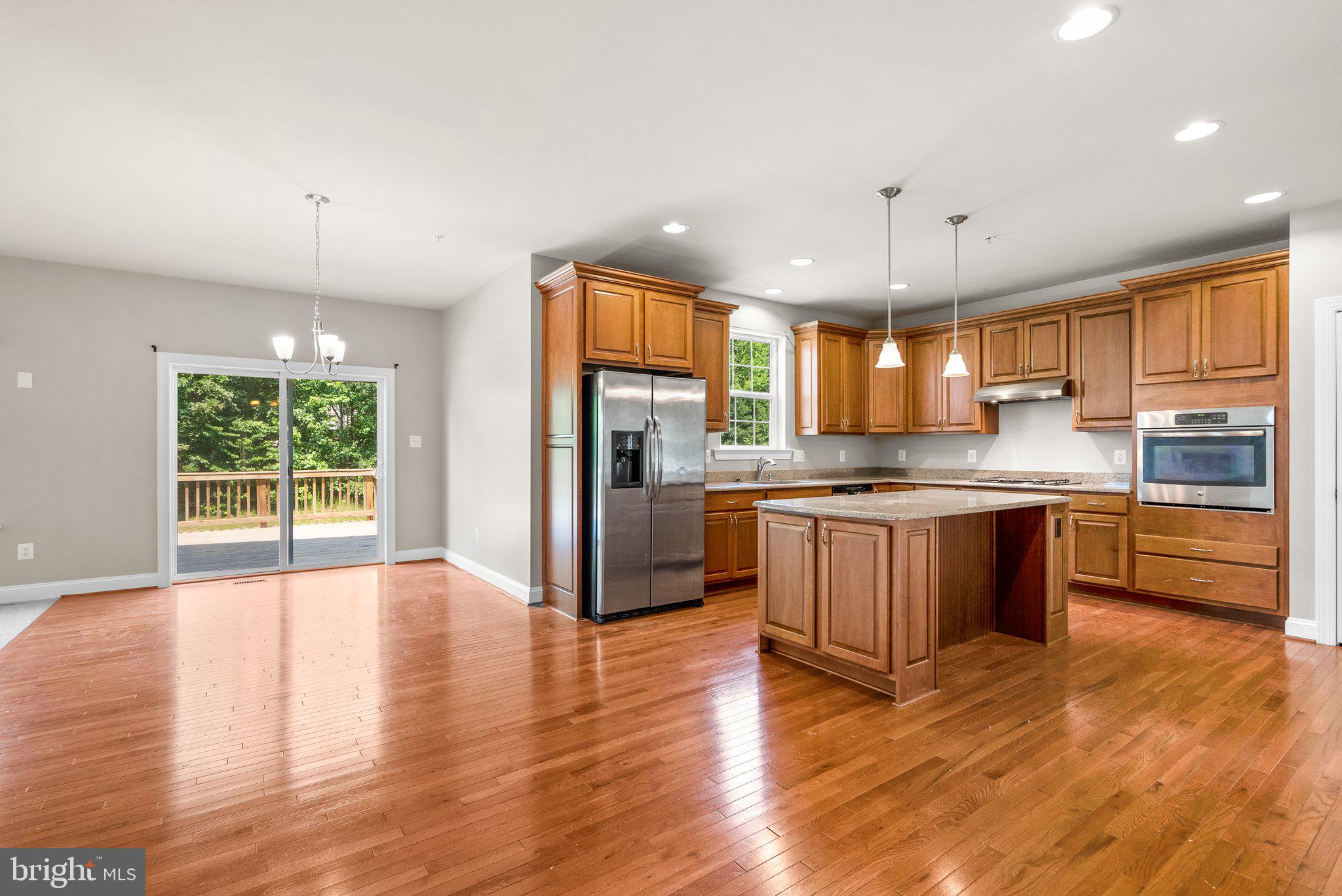 9602 Pep Rally Lane Waldorf, MD 20603 - Photo 10 of 44 a kitchen with stainless steel appliances granite countertop a refrigerator a sink dishwasher a stove top oven a large island with wooden floor and cabinets