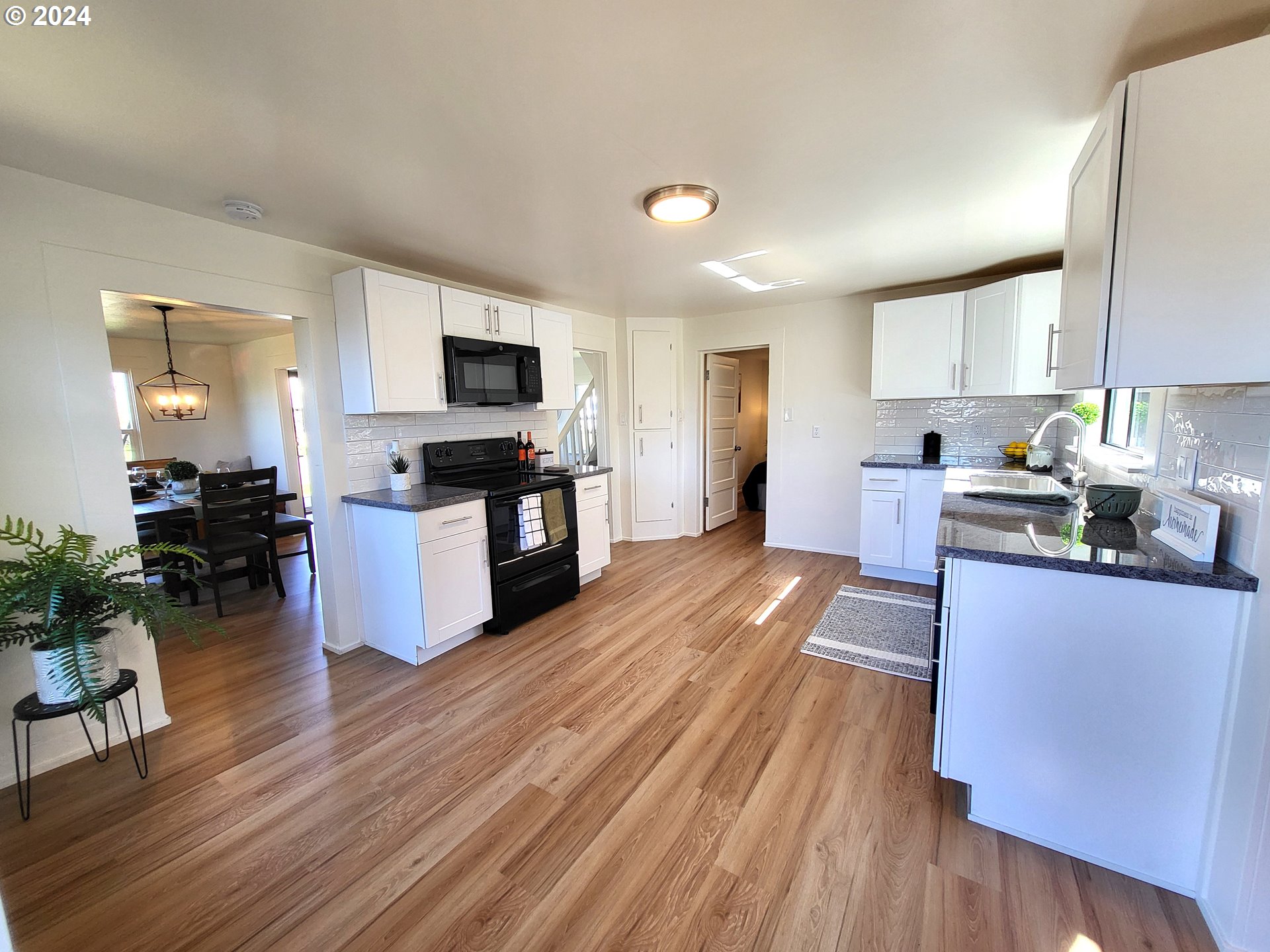 1029 A Street Springfield, OR 97477 - Photo 11 of 27 a kitchen with granite countertop a stove top oven a sink dishwasher a dining table and chairs with wooden floor