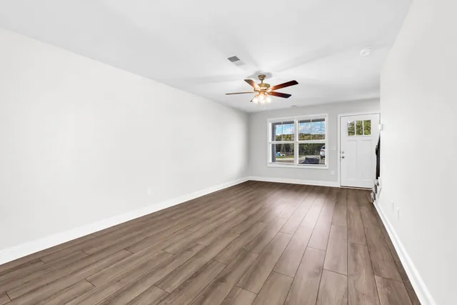 an empty room with wooden floor and windows