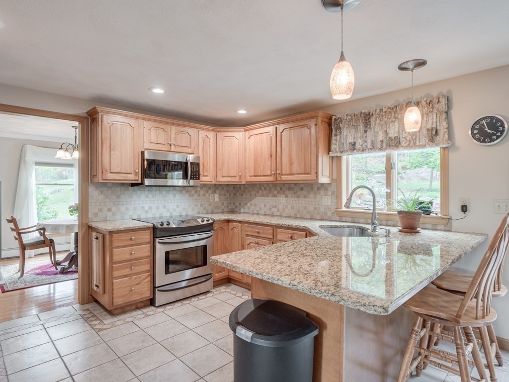 21 Scenic View Drive Pelham, NH 03076 - Photo 18 of 42 a kitchen with stainless steel appliances granite countertop a stove top oven a sink dishwasher a dining table and chairs with wooden floor